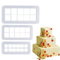 Three white geometric cookie and fondant cutters next to a three-tier cake decorated with pixelated squares