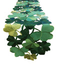Green embroidered clover cutouts table runner on a white background, close-up view