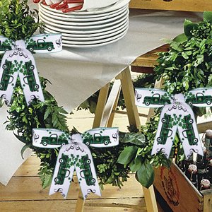 St. Patrick's Day wreath decorated with green trucks, shamrocks, and bows, set on a table with stacked plates.