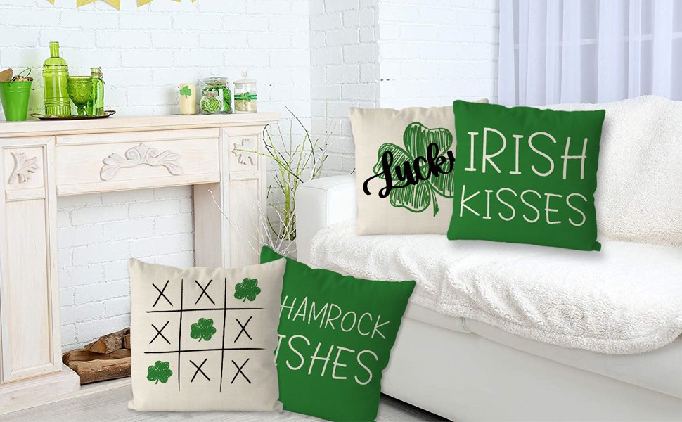 Four St. Patrick's Day themed pillow covers arranged on a sofa, featuring shamrocks and text.