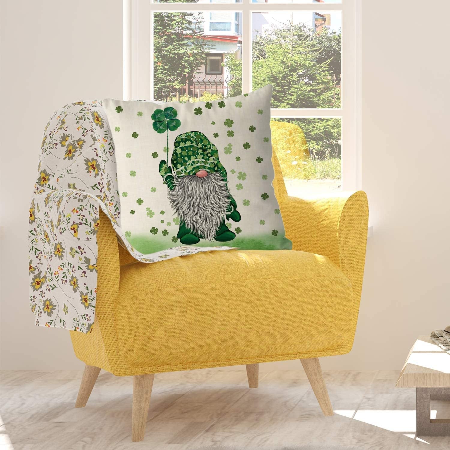 St. Patrick's Day pillow cover with a gnome holding a four-leaf clover, placed on a yellow armchair with a floral throw blanket.