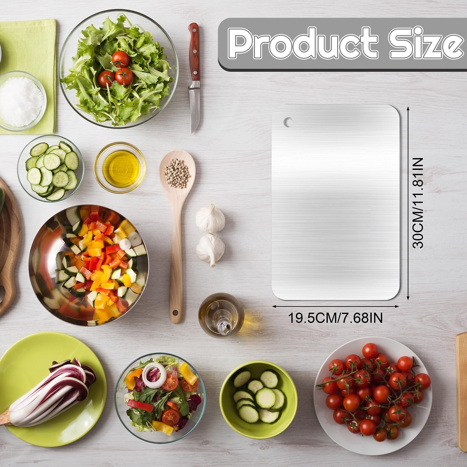Stainless steel cutting board with dimensions shown, surrounded by fresh ingredients for cooking.
