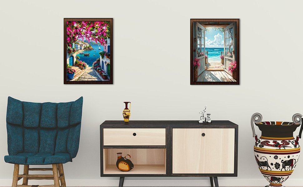 Two framed cross stitch art pieces depicting Mediterranean scenes hanging on a wall above a credenza.