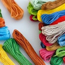 Assortment of colorful embroidery threads on a white surface, arranged in piles and loose strands.