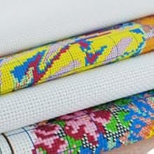 Rolled stamped cross stitch fabric with pre-printed colorful patterns and white grid fabric.