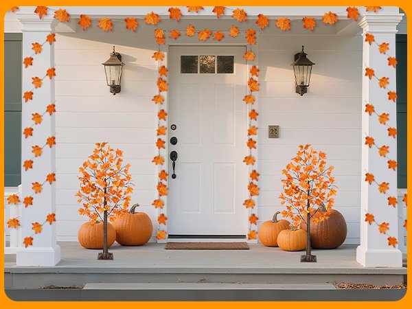 Front porch decorated for fall with maple leaf garlands and lighted trees, pumpkins.