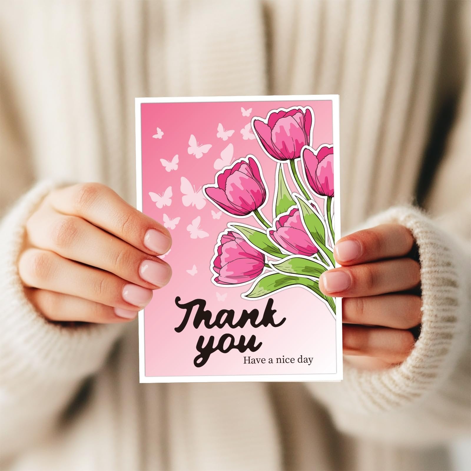 Hands holding a card with pink tulips and butterflies, reading 'Thank you Have a nice day'.
