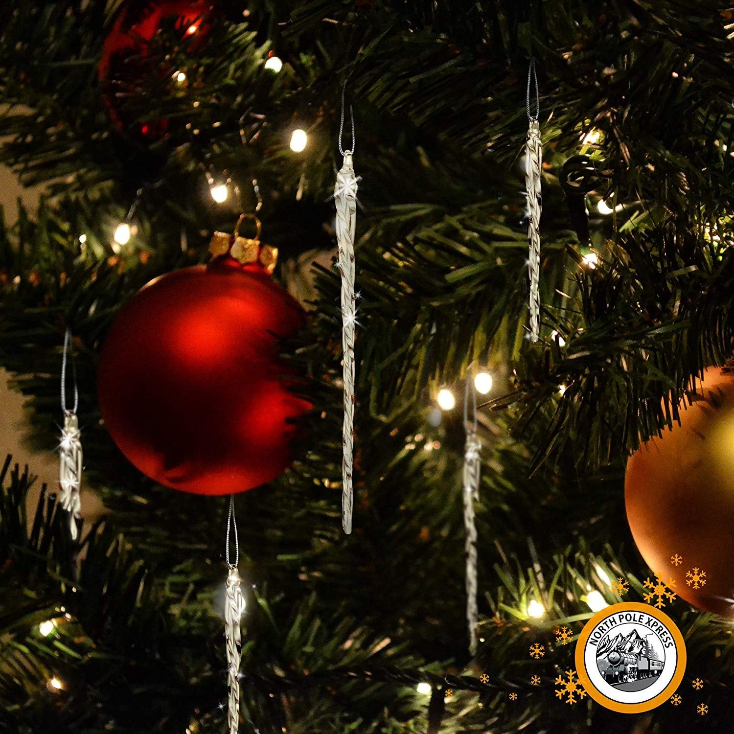 Twisted clear glass icicle Christmas ornaments hanging on a decorated tree with red and gold baubles.