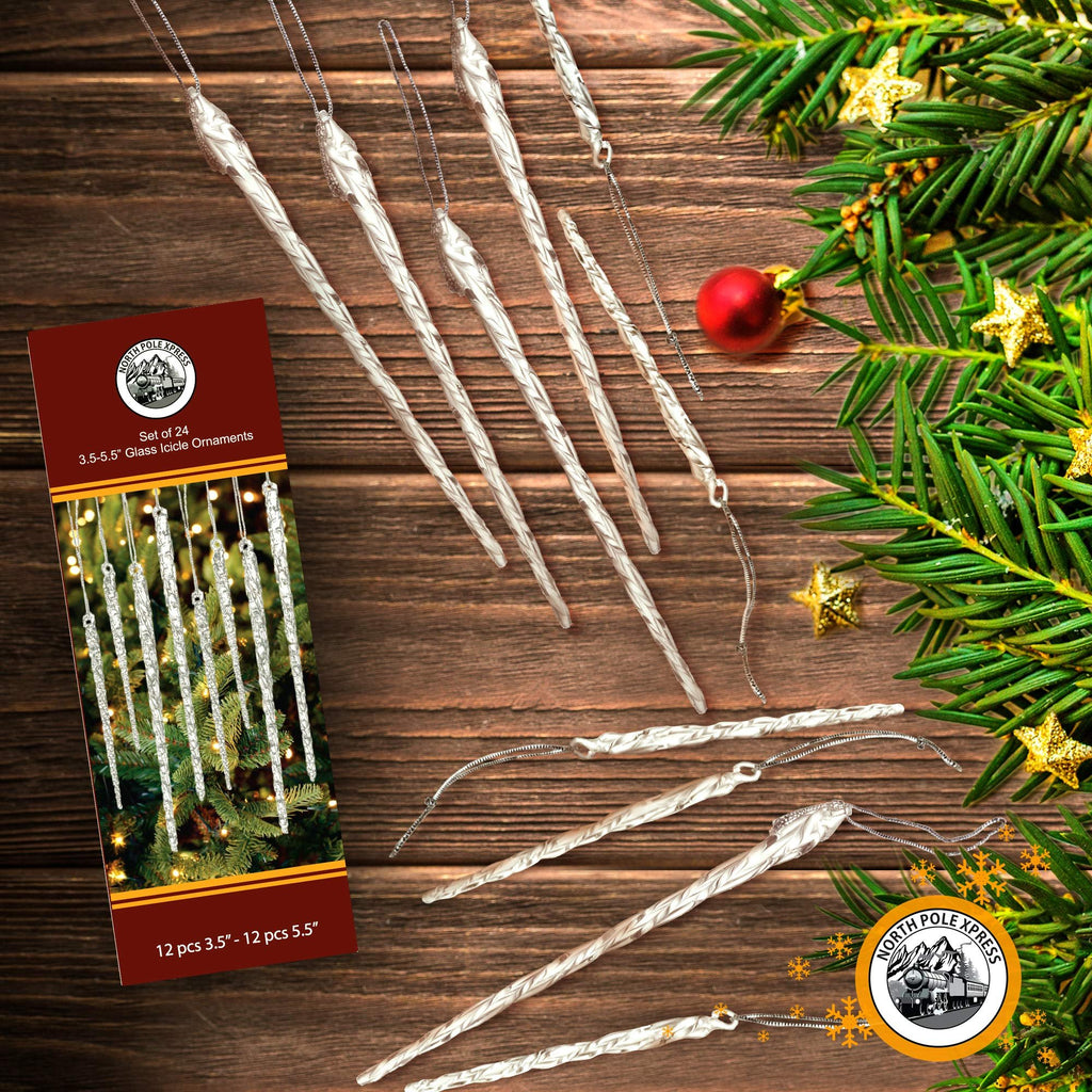 Set of 24 twisted clear glass icicle Christmas ornaments with silver cord hangers on a wooden background with pine branches and gold stars.