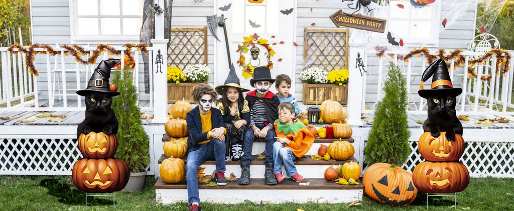 Halloween yard signs featuring black cats on pumpkins and children in costumes on porch steps