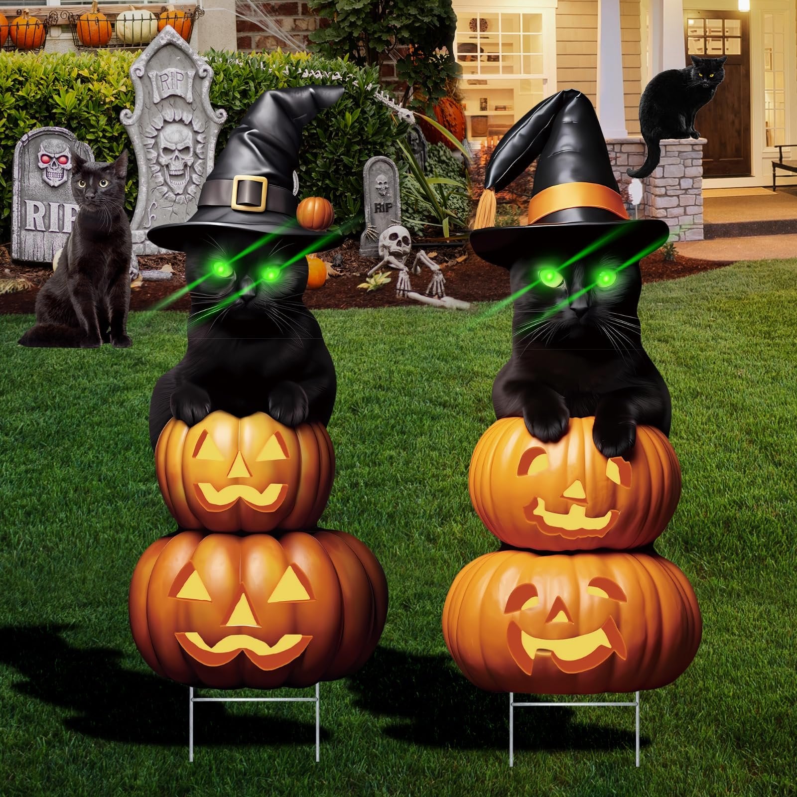 Two black cat Halloween yard signs stacked on pumpkins, wearing witch hats with green laser eyes, in a yard with tombstones.