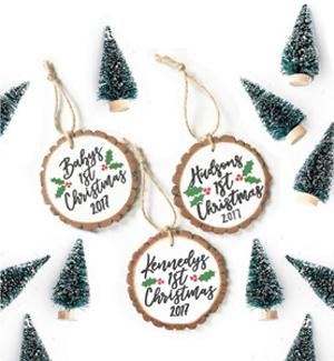 Three unfinished wood slice ornaments with custom text and small bottle brush trees scattered around.