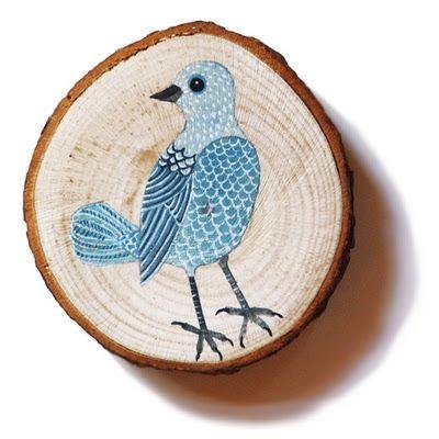 Unfinished natural pine wood slice with bark, featuring a blue painted bird design, isolated on white.