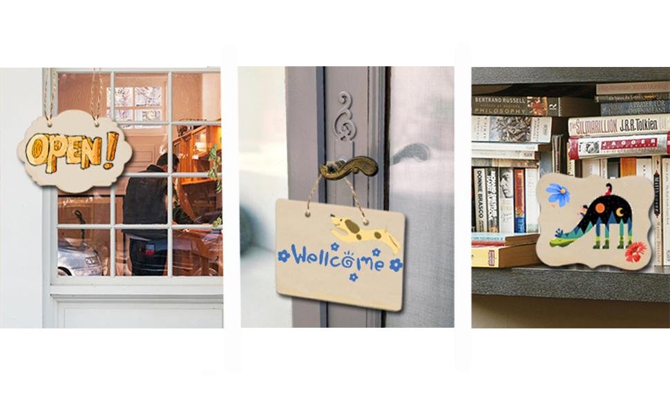Three unfinished wood ornaments: one with 'OPEN!' text, one with 'Welcome' and a dog, and one with a colorful landscape design.