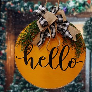 Yellow unfinished wood round door hanger with 'hello' text, greenery, and buffalo check bow