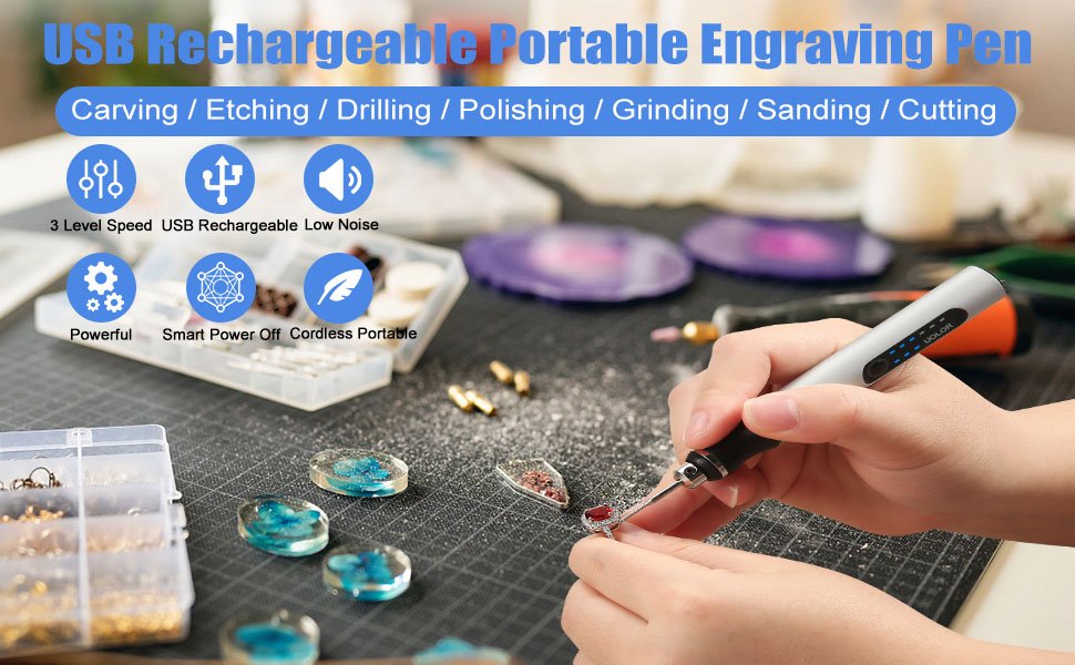 Hand holding a USB rechargeable engraving pen, working on a pendant with various craft supplies around.