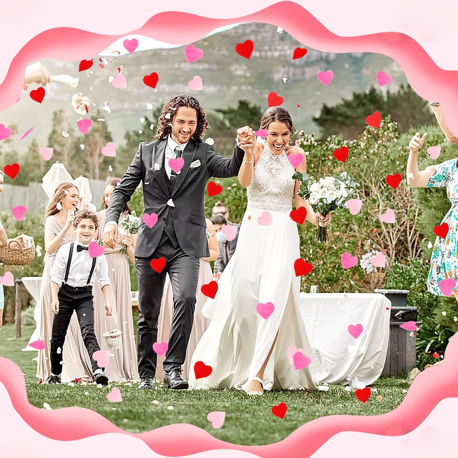 Wedding couple walking through red and pink heart confetti outdoors with wedding party