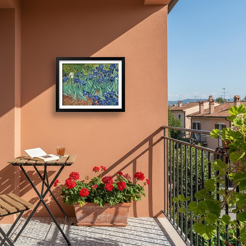 Framed Van Gogh Irises painting displayed on a terracotta wall above a small table and red flowers on a balcony.