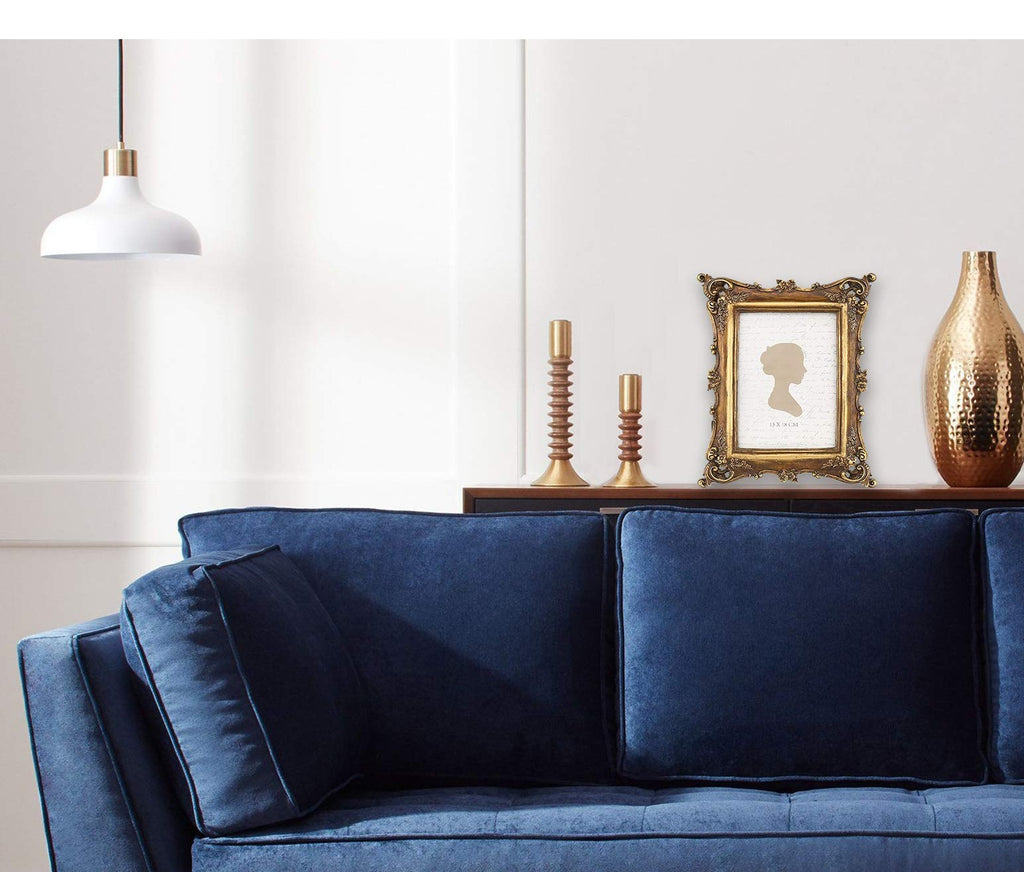 Vintage-style ornate gold picture frame displaying a silhouette on a shelf with candlesticks and a vase, in front of a blue sofa.