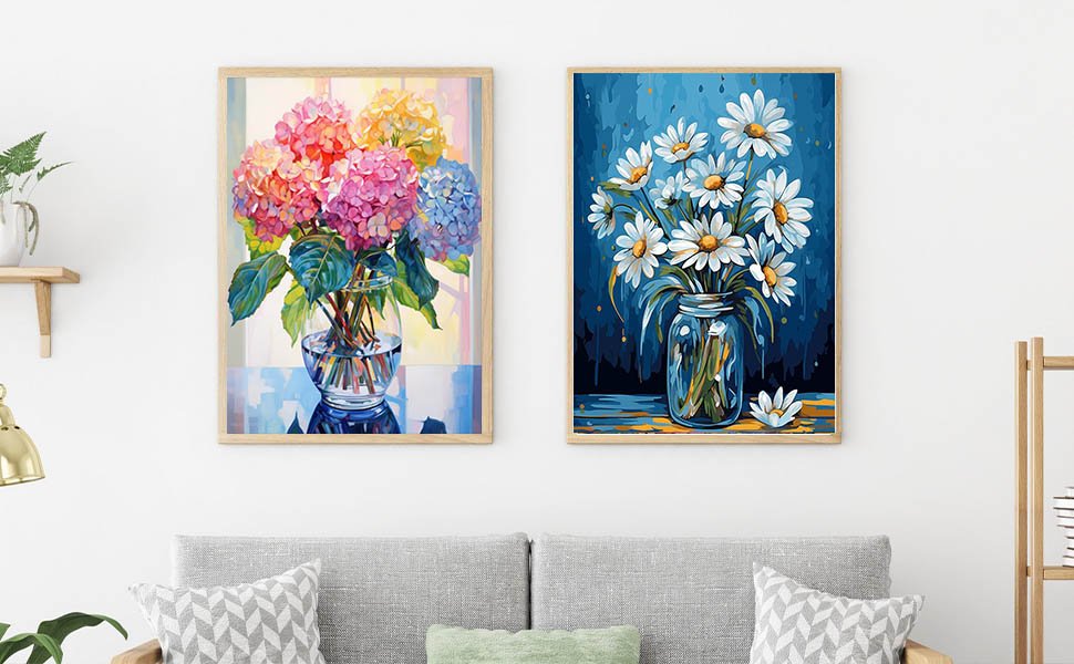 Two framed diamond paintings of flowers in vases displayed on a wall above a sofa.