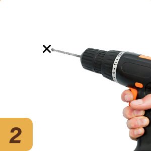 Hand holding a black and orange power drill with a drill bit, drilling a small hole marked with an X on a white background. Yellow square with the number 2 in the lower left corner.