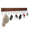 Wall-mounted key hook rack with 12 metal hooks holding keys and a cap, made of brown wood.