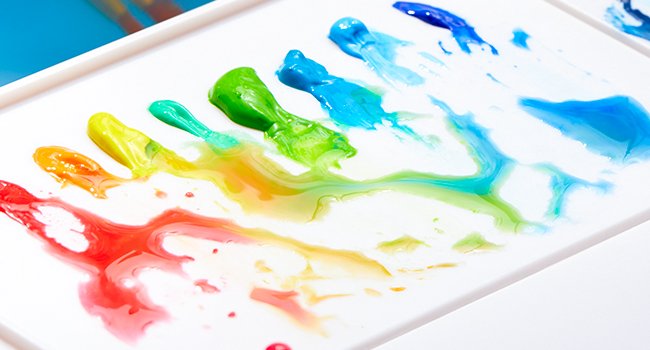 Watercolor paints swatched in rainbow colors on a white palette, showing blending and texture.