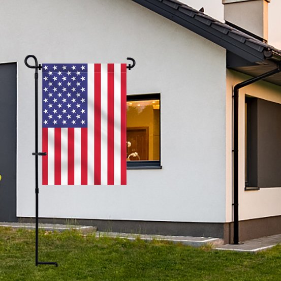 Black metal garden flag stand holding an American flag in front of a white house.