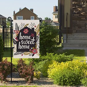 Metal garden flag stand with a 'home sweet home' flag, shown in a yard setting.