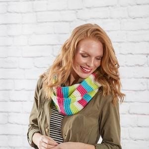 Woman wearing a colorful striped infinity scarf knitted from white acrylic yarn