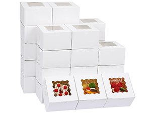 Stack of white bakery boxes with clear windows, three boxes in front are filled with treats.