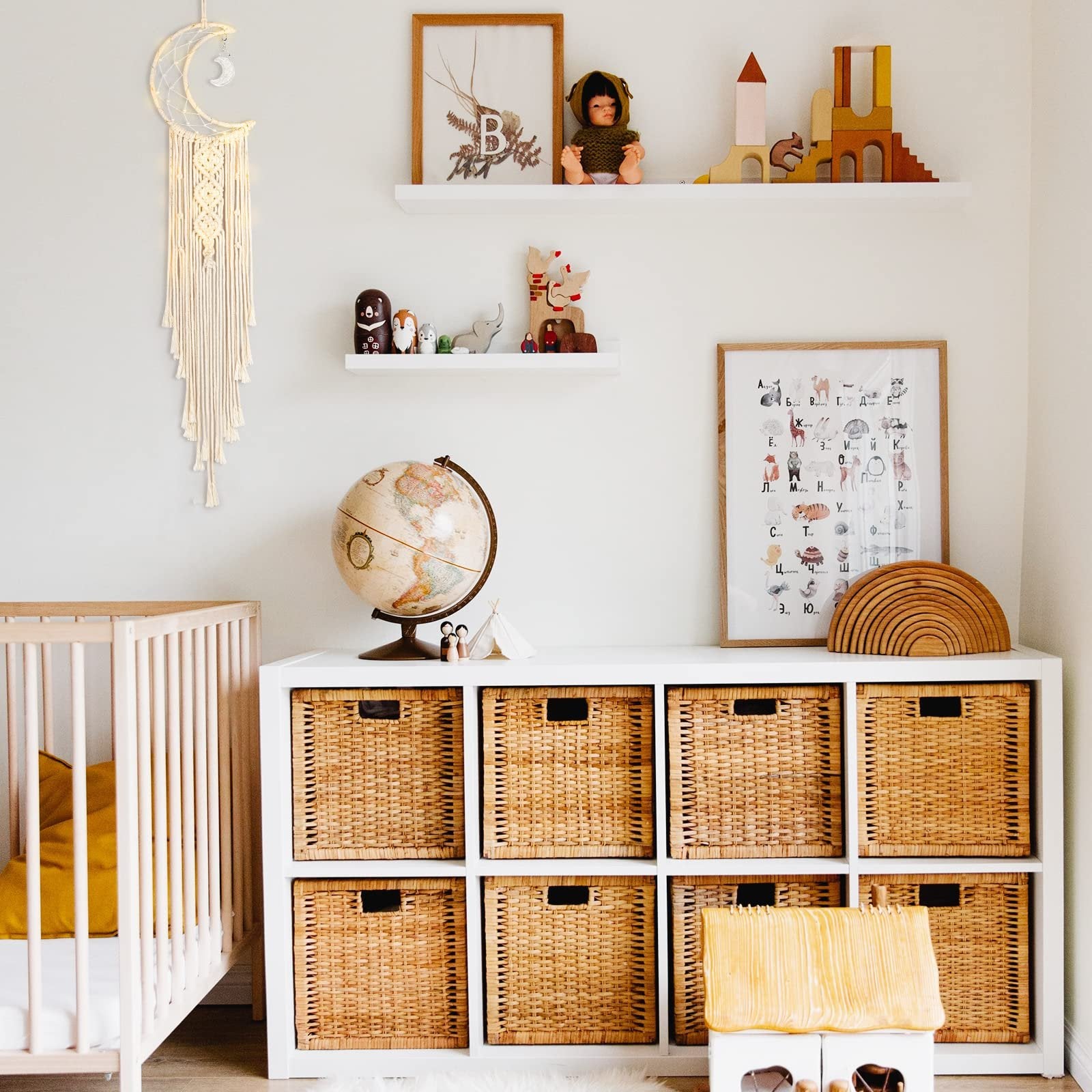 Macrame crescent moon dream catcher with string lights and long tassel hanging in a nursery next to a crib.