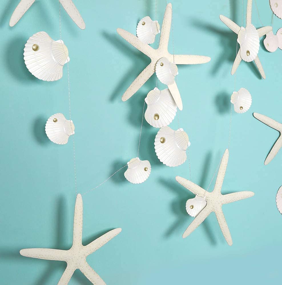 White starfish and seashell paper garland strings against a teal background, close-up view.