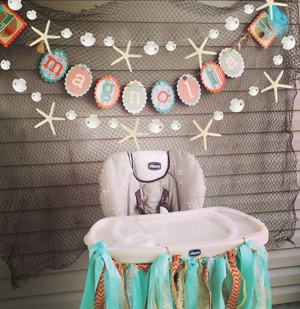 Nautical themed high chair decorated with starfish and seashell garland for a party
