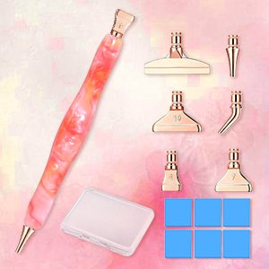Diamond painting pen kit with pink marbled handle, six rose gold metal tips, wax clay squares, and a clear storage box on a pink background.