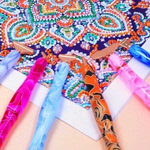 Diamond painting pens and tools arranged over a colorful patterned canvas, close-up view.