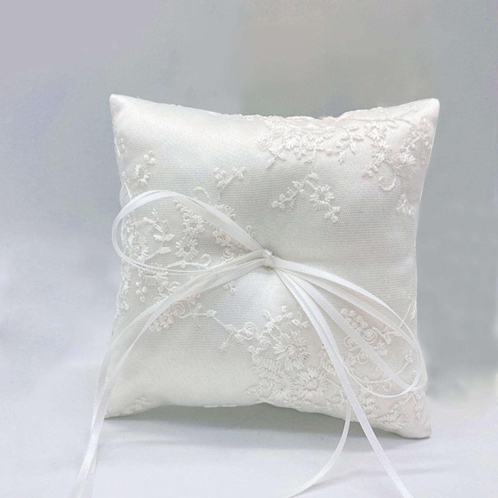 White satin ring bearer pillow with floral lace embroidery and ribbon bow, shown from the front.