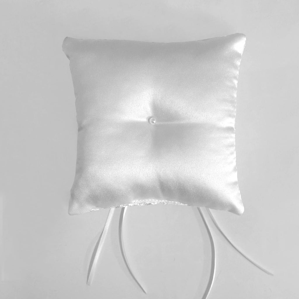 White satin ring bearer pillow with floral lace trim and ribbon bow, shown from a top-down angle on a plain background.