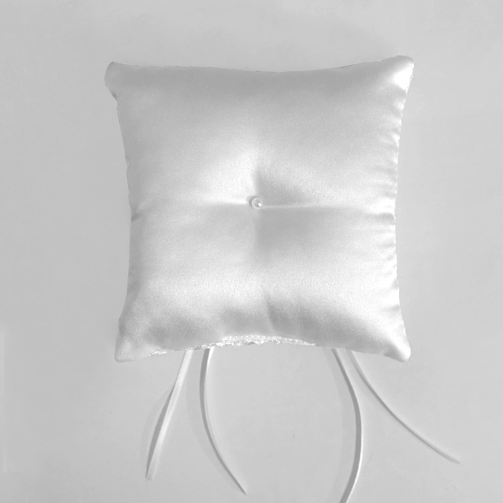White satin ring bearer pillow with floral lace trim and ribbon bow, shown from a top-down angle on a plain background.