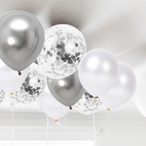 Group of white, silver, and confetti latex balloons floating upwards against a white ceiling.