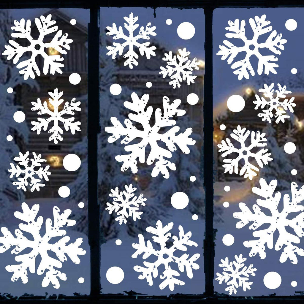 White snowflake and circle window clings applied to a window with a snowy cabin scene visible through it.