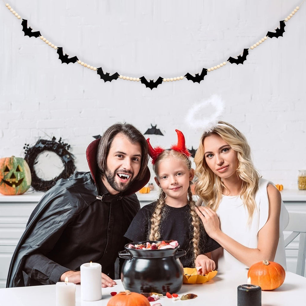 Family in Halloween costumes with a wood felt bats bead garland hanging above them.