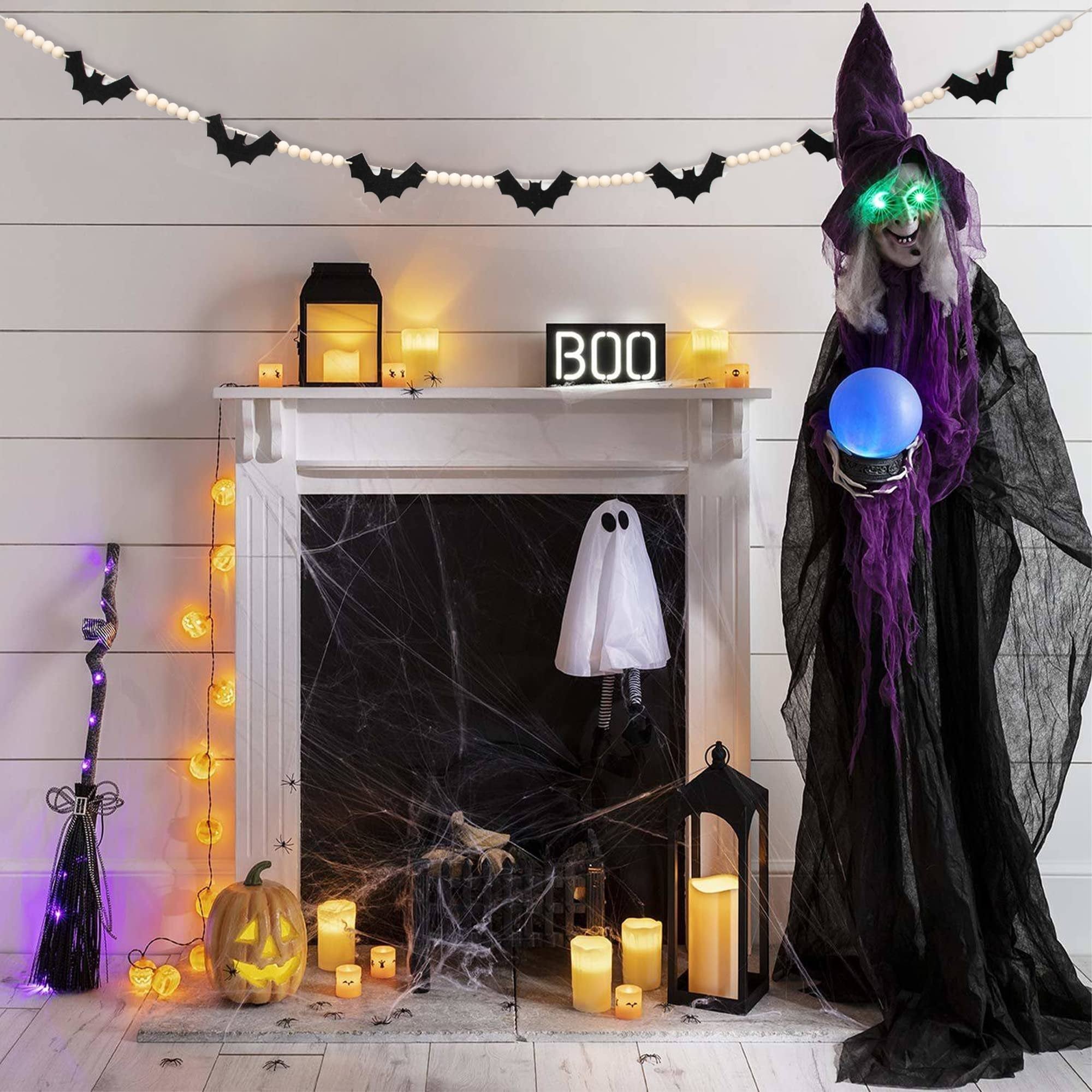Halloween fireplace decor with bat garland, witch figure, ghost, pumpkin, and lanterns