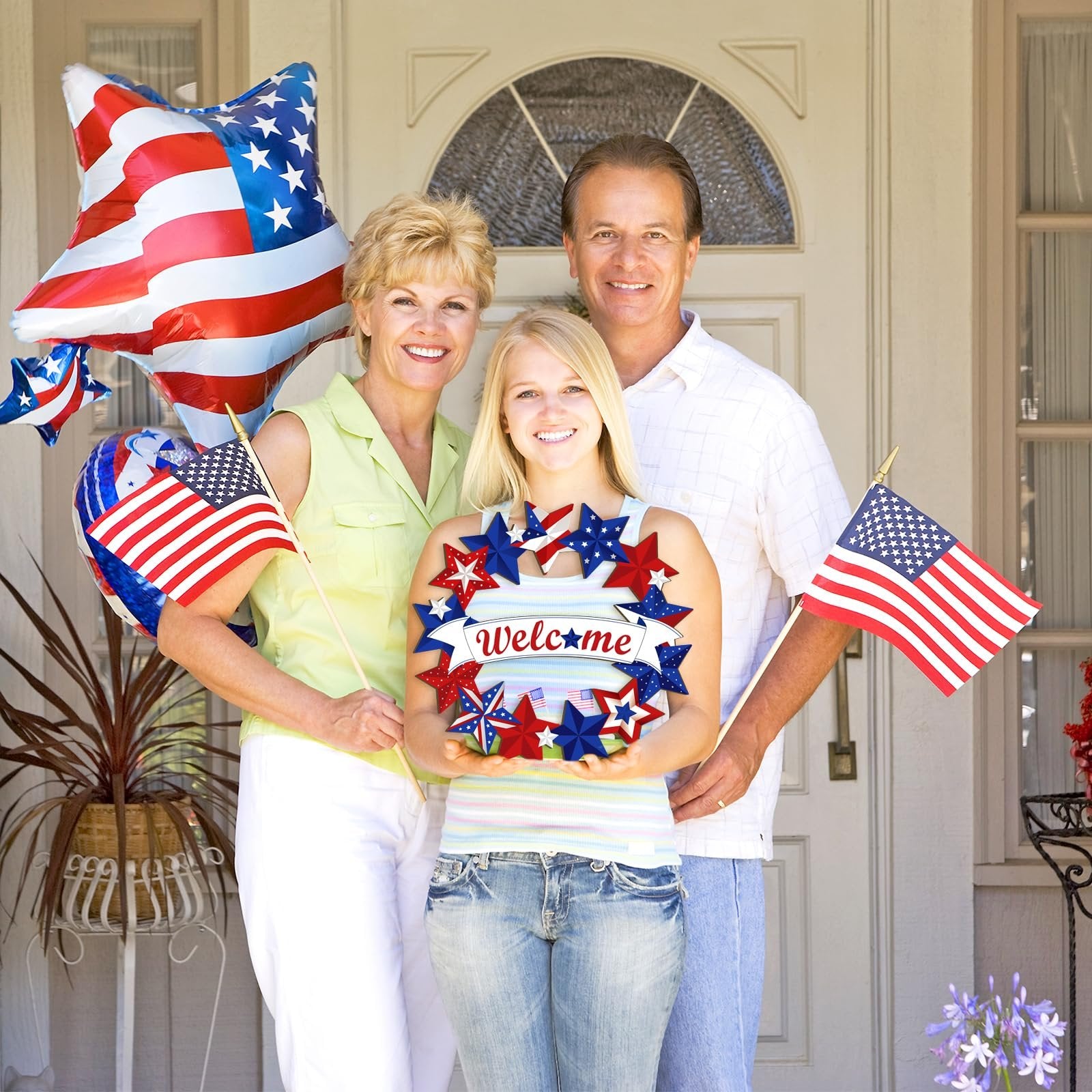 Family holding a patriotic star wreath with 'Welcome' text and American flags, standing in front of a door.