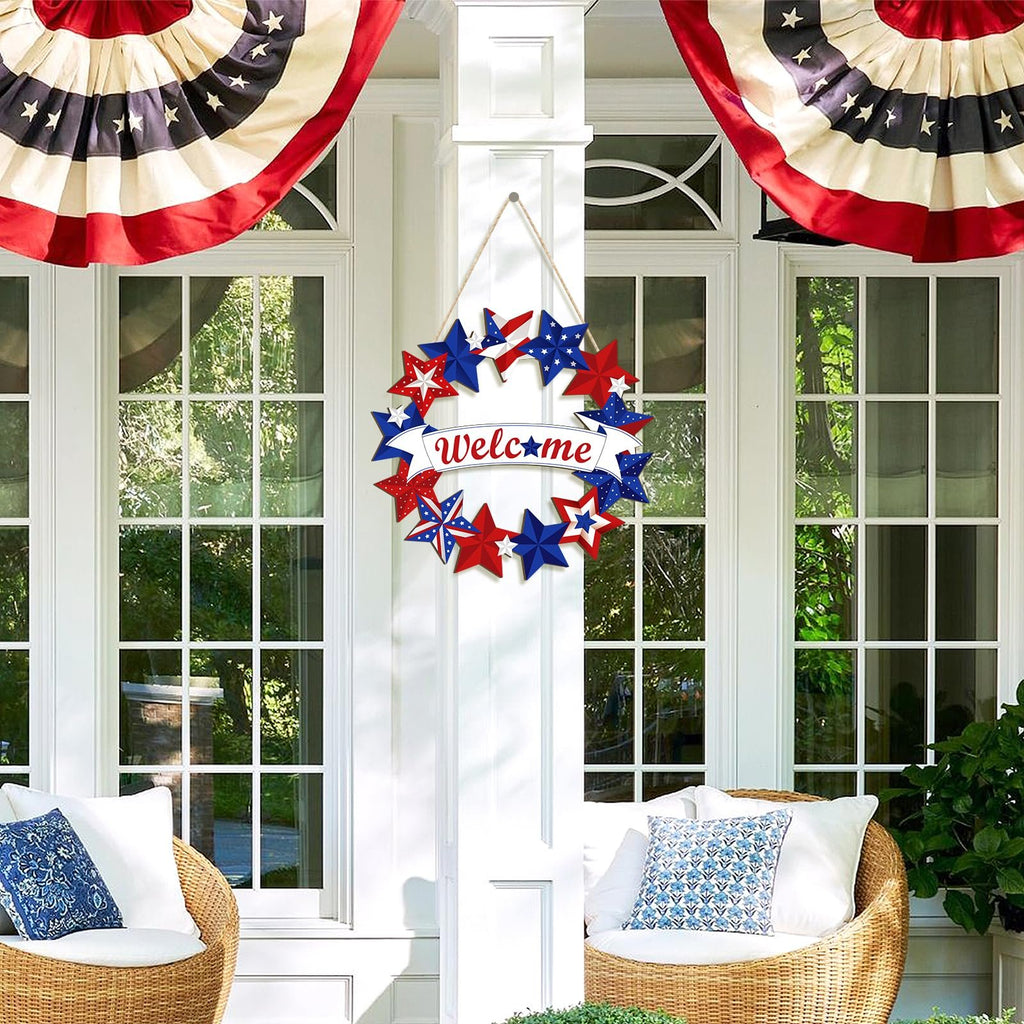 Fourth of July star wreath with 'Welcome' banner hanging on a white door between two windows, flanked by patriotic bunting.