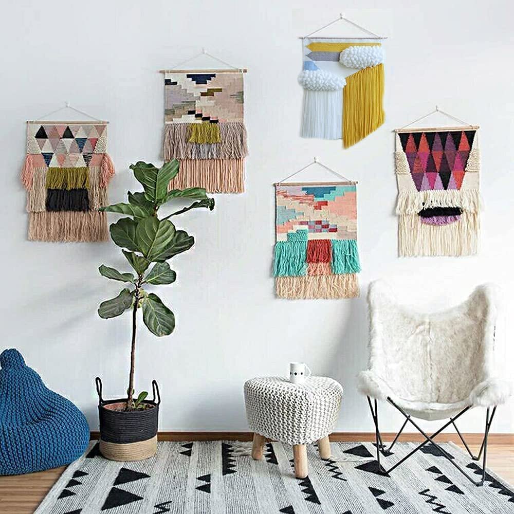 Five woven wall hangings displayed on a white wall above a rug, plant, and chair.
