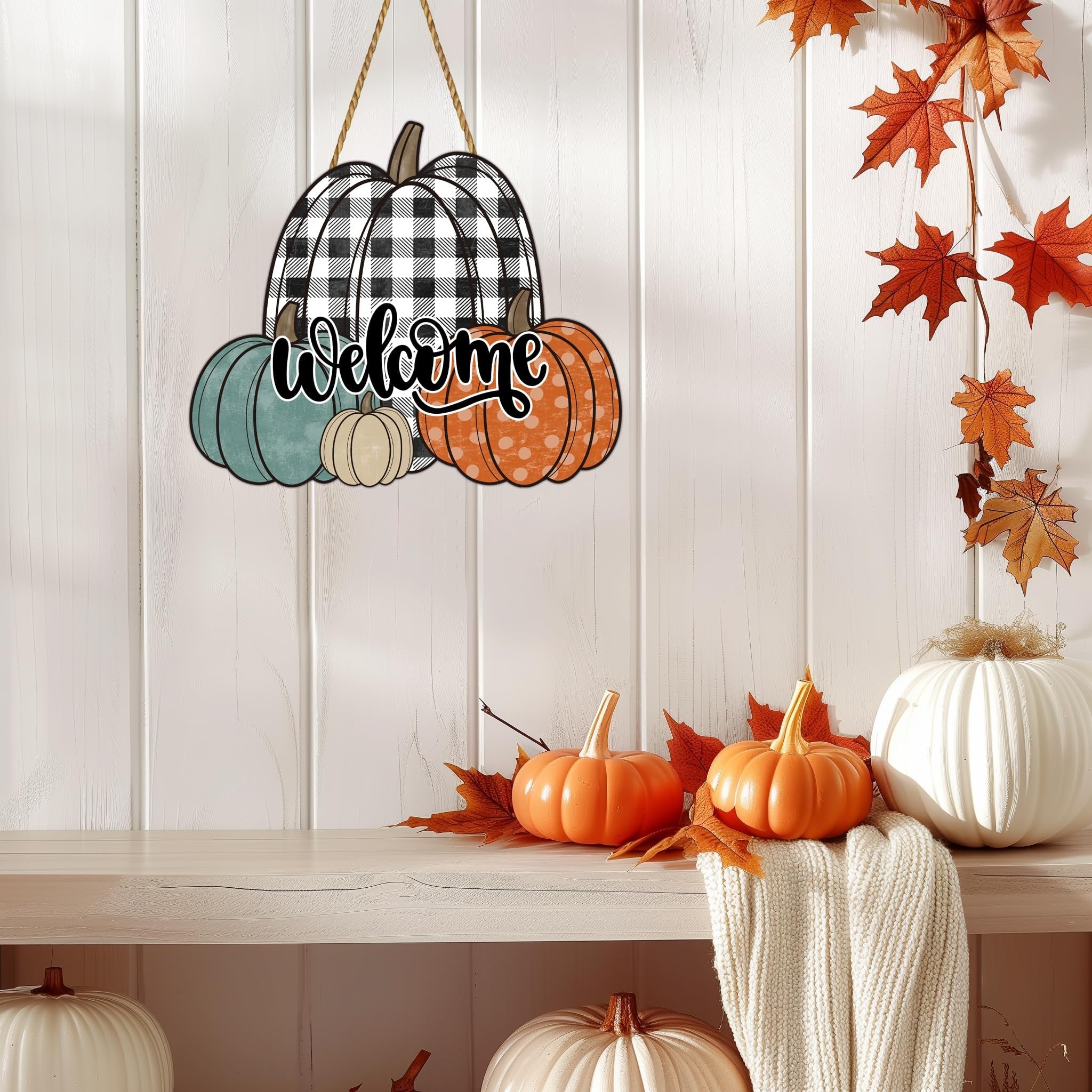 Wooden pumpkin welcome sign with buffalo plaid and polka dot pumpkins, hanging on a white paneled wall with fall leaves.