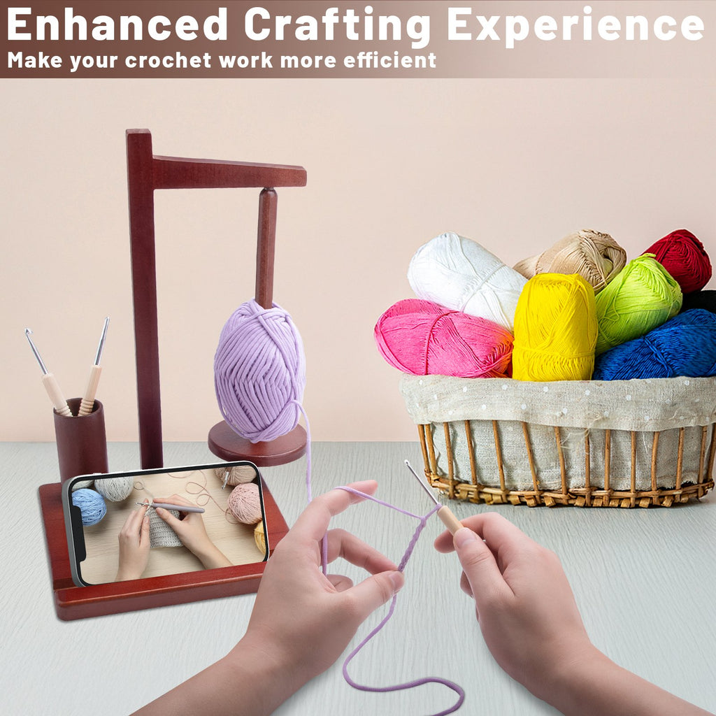 Wooden yarn holder with a ball of purple yarn, basket of colorful yarn, crochet hooks, and a smartphone displaying a crochet tutorial.