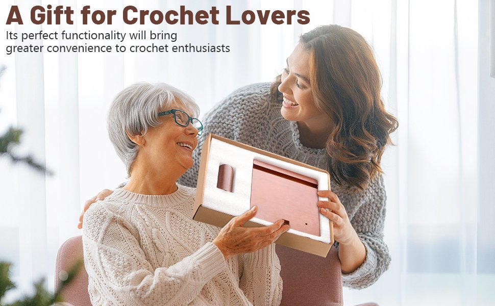 Two women smiling as one presents a wooden yarn holder with phone stand in a box