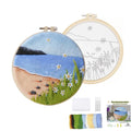Needle felting kit with finished beach scene embroidery hoop and blank hoop with outline, plus wool roving, felting needles, foam pad, and instructions.